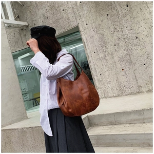 Detail of vintage brown textured leather tote bag with side metal zipper and sleek shoulder strap