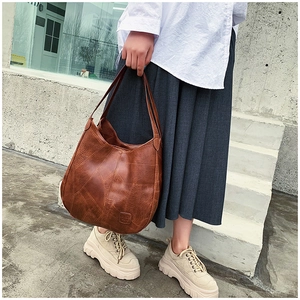 Outdoor street style view of a brown retro textured hobo bag with patchwork design