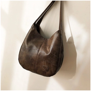 Detail of dark brown vintage faux leather shoulder bag with patchwork texture and round base