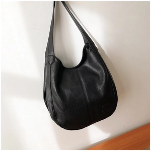 Close-up of a black textured faux leather hobo bag with a minimalist square embossed logo