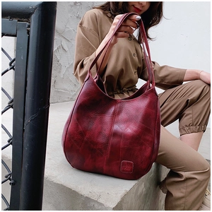 Close-up of vintage burgundy faux leather tote bag with embossed logo on outdoor steps