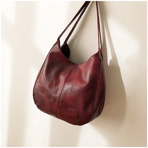 Detailed macro view of the vintage wine red leather texture and stitching on tote bag