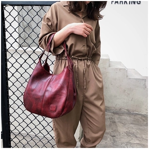 Detail of the dark red vintage tote bag showing stitched leather and square embossed logo