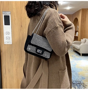 Dettaglio di una borsa a tracolla nera con strass e catena argentata indossata da modella