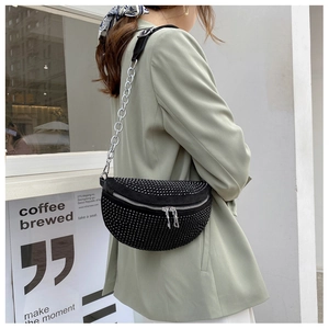 Streetstyle-Aufnahme einer schwarzen Strass-Umhängetasche mit silbernem Metallkettenriemen