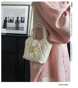 Close-up of cream quilted mini bag with gold chain strap on a stylish model