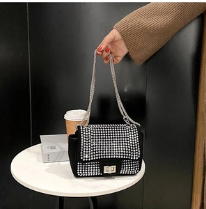Dettaglio di una borsa a tracolla con strass brillanti, catena argento e chiusura