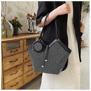 Detail of a black rhinestone tote bag with a small round coin purse shown in a home setting