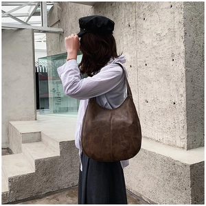 Detail of vintage brown leather hobo shoulder bag with textured stitching on model