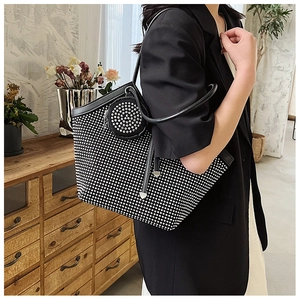 Detail of a black rhinestone tote bag with a small coin purse and leather shoulder strap