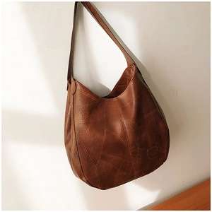 Detail of vintage brown leather texture and logo embossing on hobo tote bag