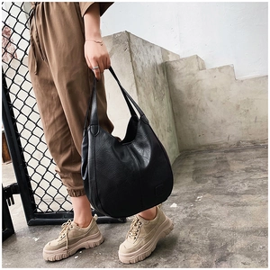 Detail of soft black lychee grain leather on a large capacity minimalist hobo tote bag