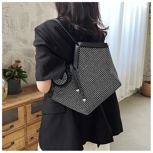 Detail view of a black rhinestone tote bag with a small matching pouch worn by a model