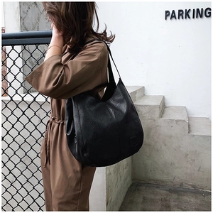 Close-up of black PU leather tote bag showing fine texture and embossed logo patch