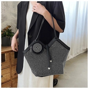 Macro view of glittering rhinestones on a large black tote bag with matching round charm