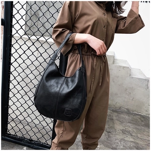 Detailed side view of black tote bag with irregular patchwork texture on a model