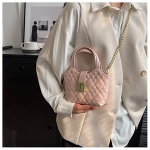 Detail of pink quilted handbag showing golden twist lock and elegant chain strap