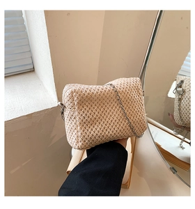 Detail of woven straw shoulder bag featuring a silver metal chain and zipper closure