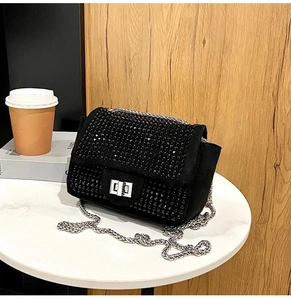 Dettaglio borsa a tracolla nera con strass, catena argento e chiusura a rotazione in metallo