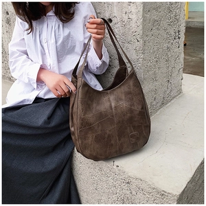 Detailed view of the dark brown leather tote bag with vintage texture and stitching