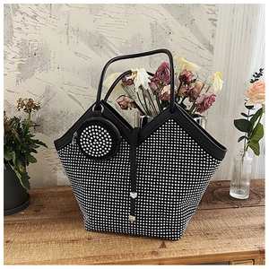 Macro detail of rhinestone-embellished black tote bag with matching round coin purse charm
