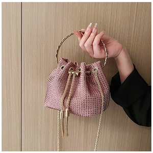 Détail du sac seau en strass rose avec poignée ronde dorée et glands à franges