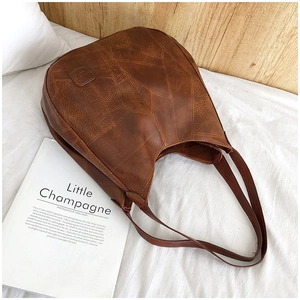 Macro detail of brown retro leather tote bag featuring patchwork stitching and flat handles