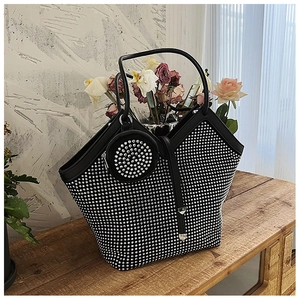Detail of black rhinestone tote bag with matching round coin purse on a wooden surface