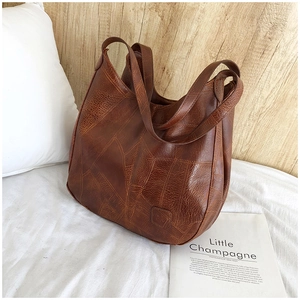 Detail showing the vintage dark brown leather texture and stitching of the large tote bag