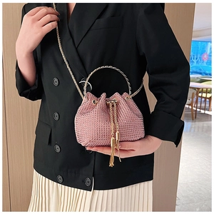 Détail du sac seau rose en strass avec pompons métalliques et bandoulière chaîne élégante