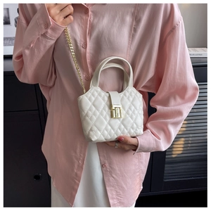 Close-up of white quilted mini bag with golden chain strap and metallic buckle closure