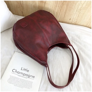 Detailed view of dark red vintage leather tote with geometric embossed lines on white bedding