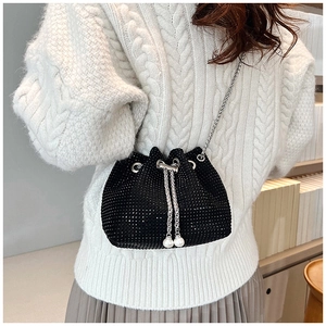 Détail du sac seau noir en strass avec cordon en perles et chaîne argentée sur modèle