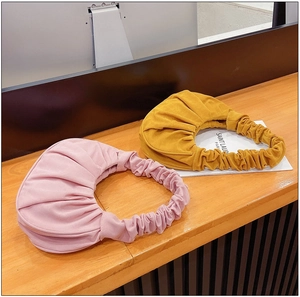Detail van geplooide wolktassen in roze en geel met zachte plooitextuur en handvaten
