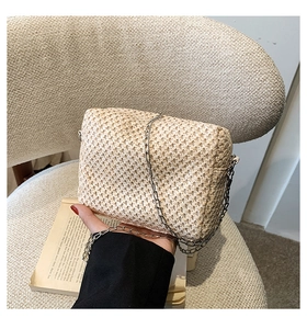 Detail of beige straw woven square bag with a silver metal chain strap for summer vacation