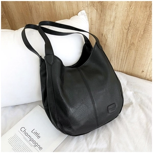 Close-up of black leather tote bag showing rich lychee texture and embossed logo plate