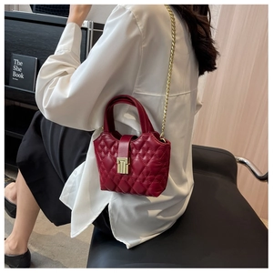 Detailed view of red quilted handbag with golden chain strap on a stylish model