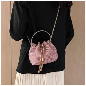 Gros plan du sac seau en strass roses avec poignée en métal doré et pompons à franges
