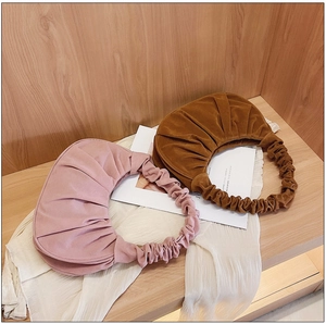 Gedetailleerde close-up van roze en bruine geplooide cloud bags op houten achtergrond