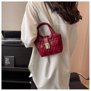 Detail of red quilted leather mini bag with gold chain strap on a lifestyle background