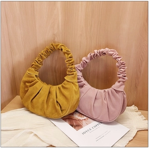 Detailweergave van de geplooide hobo-tassen in geel en roze van zachte suède-achtige stof
