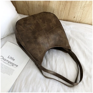 Detail shot of a brown vintage tote bag showing retro texture and stitching on bed