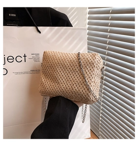 Close-up of woven straw handbag texture with silver metal chain strap and minimalist design
