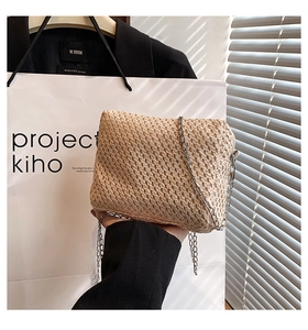 Detailed view of handmade raffia weave texture and silver chain strap on a summer straw bag