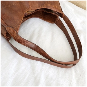 Detail view of large brown tote bag showing textured PU leather and inner zip pocket