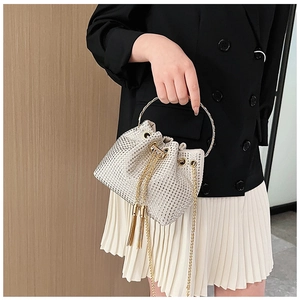 Détail d'un sac seau étincelant en strass avec des poignées dorées rondes en métal