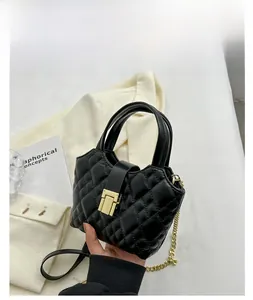 Detail of black quilted leather mini bucket bag with gold clasp and chain strap