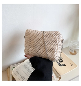 Detail of beige woven straw cloud bag with silver metal chain strap for summer beach fashion