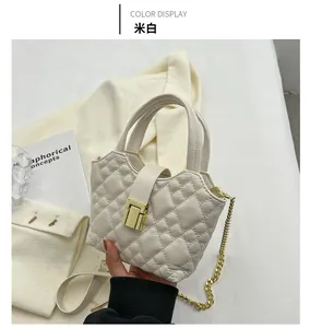 Detail of cream white quilted handbag with gold square buckle and chain strap