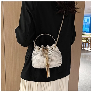 Détail du sac seau crème à strass avec poignée en anneau doré et finitions à franges
